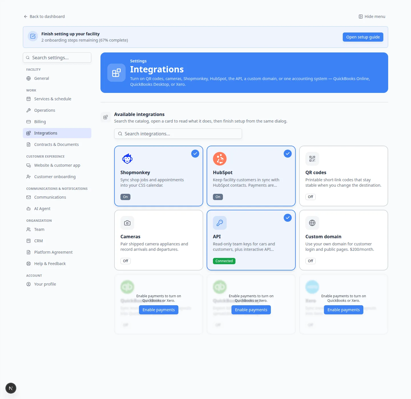 Integrations settings page with search box and cards for Shopmonkey, HubSpot, QR codes, Cameras, API, Custom domain, and locked QuickBooks and Xero cards